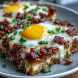 Loaded hash brown skillet with gooey cheese, crispy bacon, and sunny-side up eggs.