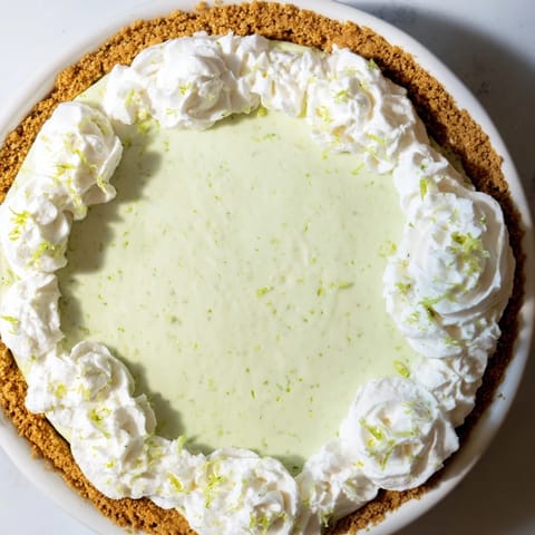 A slice of Key Lime Pie topped with whipped cream, ready for a delicious dessert.