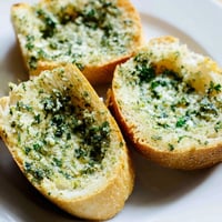 Golden, crispy garlic bread slices, slathered in herb butter, ready to be served warm.