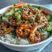 Freshly grilled shrimp over fluffy jasmine rice in this Asian Shrimp Bowl, topped with crisp edamame, cucumber, and carrots drizzled with tangy ginger-sesame dressing.