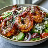 Freshly grilled shrimp and crumbled feta top a vibrant Greek Shrimp Bowl with crisp cucumbers and tomatoes.